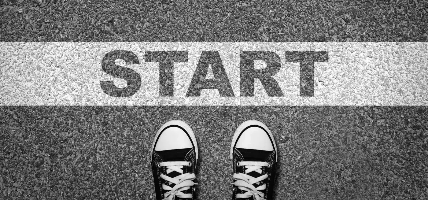 Pair of trainers standing on road printed with the word 'Start' 