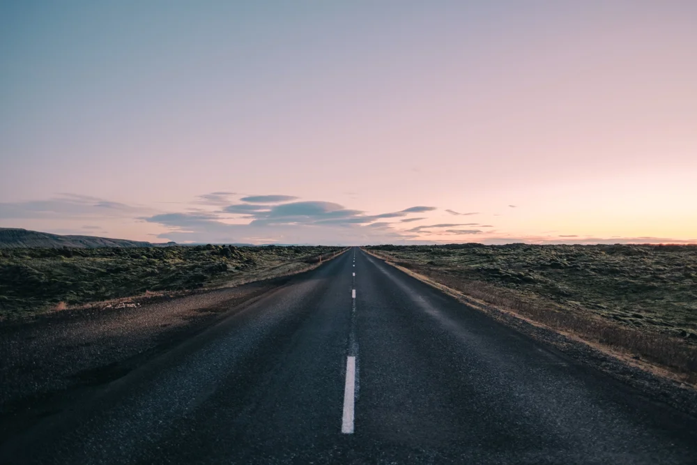 Empty Road Amidst Field Against Sky Sunset