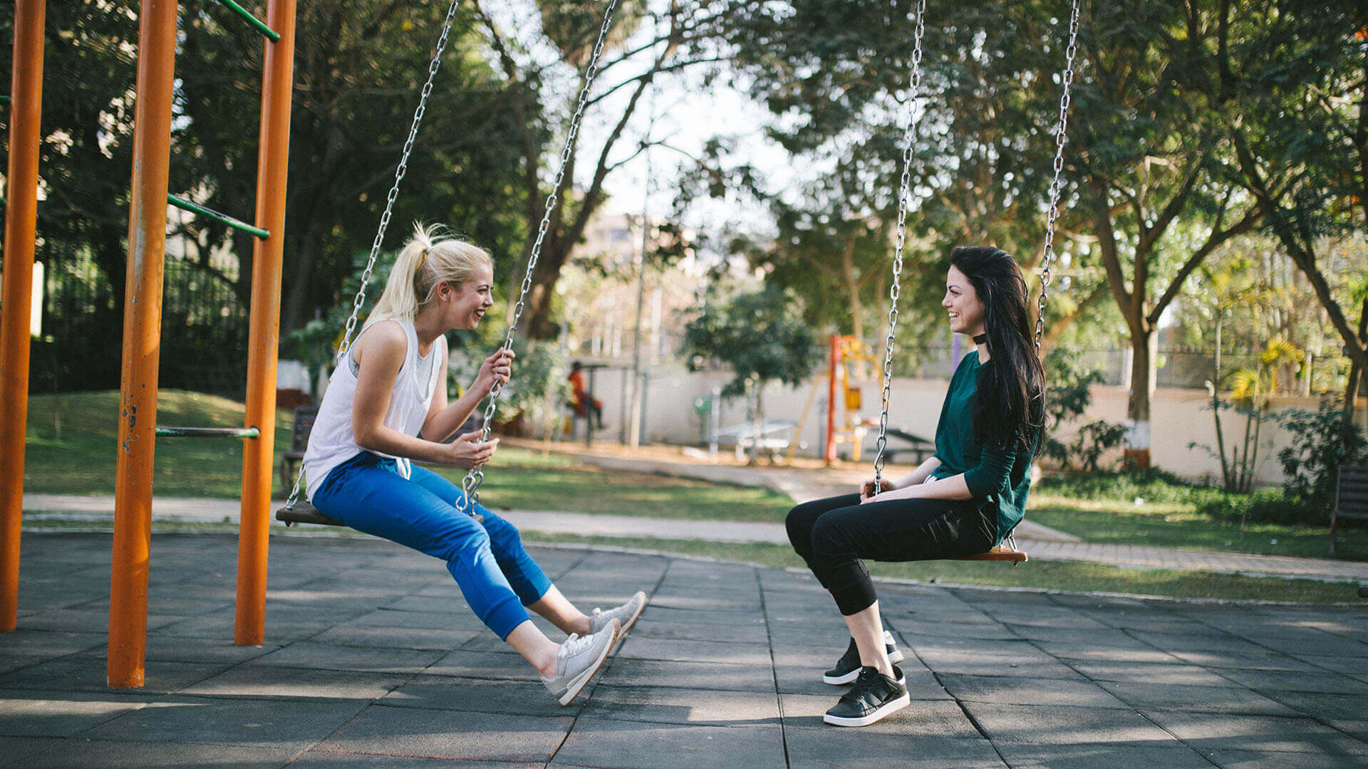 Two women facing each other on swings