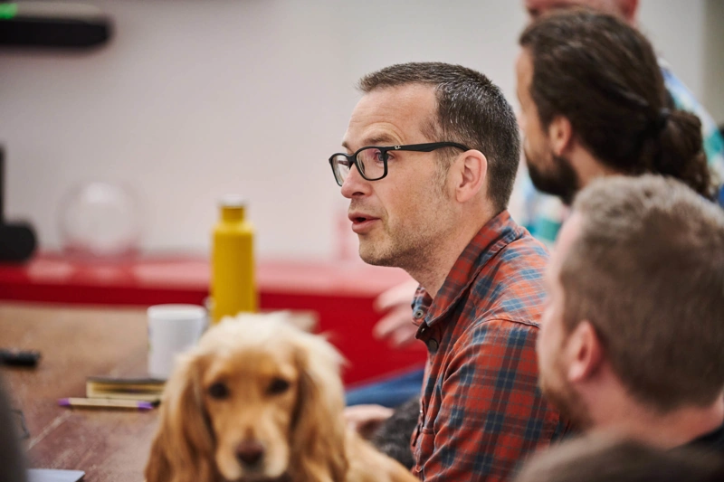 Nathan Baranowski speaking to the team with dog in the foreground looking at the camera